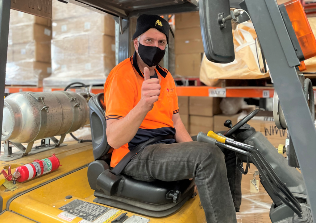 Employee with a disability on a forklift doing a thumbs up